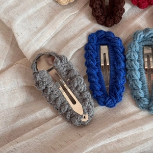 Detailed view of handmade knitted oval hair clips showing textured crochet craftsmanship