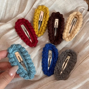 7-piece set of handmade crochet hair clips in vibrant colors on a linen fabric