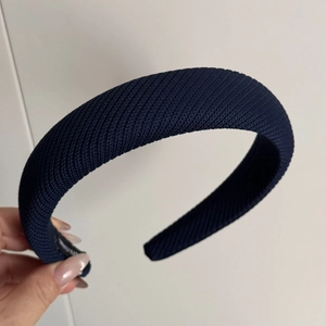 Détail d'un serre-tête en tricot côtelé bleu marine montrant la texture du tissu