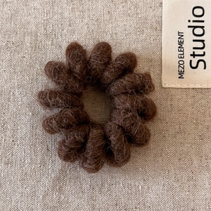 Détail d'un élastique spirale en peluche marron foncé avec texture douce sur lin