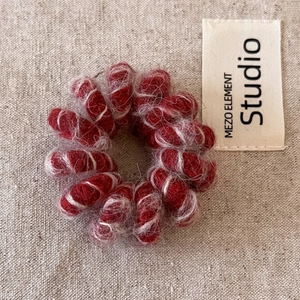 Détail d'un élastique spirale en peluche rouge avec texture douce sur fond de tissu beige