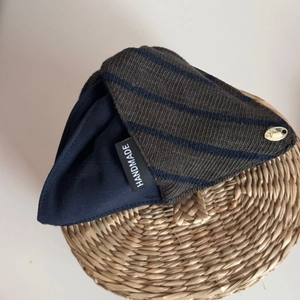 Detail of handmade knit fabric with olive and blue stripes and a gold metal nameplate