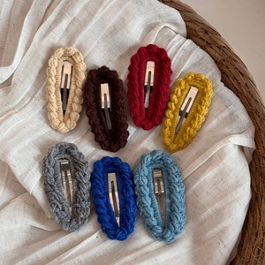Macro shot of seven handmade knit hair clips in assorted autumn colors in a woven basket