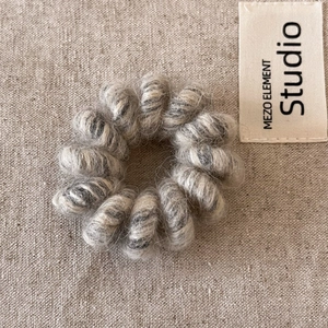 Vue détaillée d'élastiques spirale en peluche gris sur fond de lin minimaliste