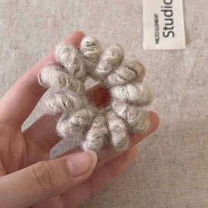 Vue détaillée de l'élastique spirale en peluche beige avec une texture tricotée douce