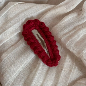 Close-up of deep red hand-knitted crochet texture on a metallic oval BB hair clip