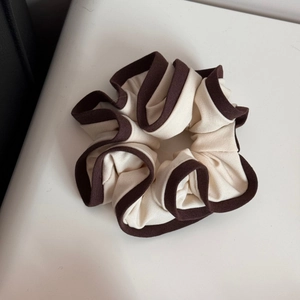 Detailed close-up of large cream cloth scrunchie with contrast brown edge and cotton texture