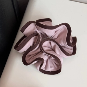 Detail of light purple scrunchie with dark brown piping and soft pleated knit fabric