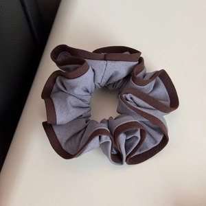Close-up of gray-purple scrunchie with dark brown piping and high-elasticity fabric texture