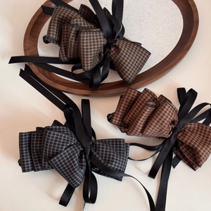 Close-up of vintage plaid bow hair clips with pleated edges and black satin ribbons