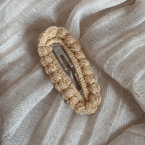 Close-up of beige hand-woven crochet hair clip with a vintage wavy textured knit pattern
