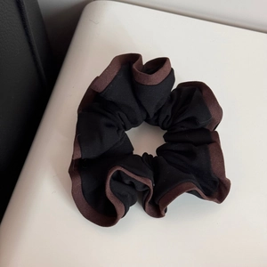 Detailed shot of large black scrunchie with brown piping and thick fabric texture
