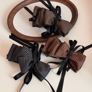 Detail of elegant houndstooth plaid bow hair clips with black satin ribbons on wood