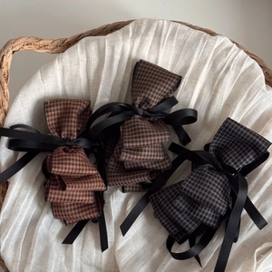 Detail view of large plaid bow hair clips in brick red, brown and grey tones