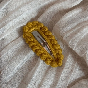 Detailed macro view of ginger yellow hand-knitted wool hair clip with metal BB clip