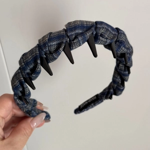 Detail of blue tartan fabric headband with black punk spikes and hand made label