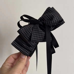 Detail view of large checkered bow hair clip with black ribbons in retro style