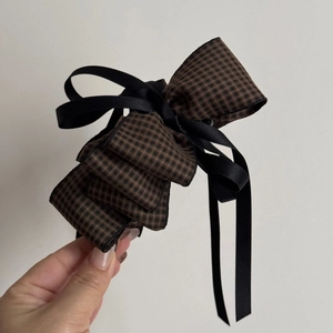 Detail of a vintage houndstooth bow hair clip with layered black satin ribbon textures