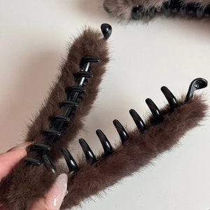 Dettaglio della molletta per capelli in peluche marrone scuro con denti robusti
