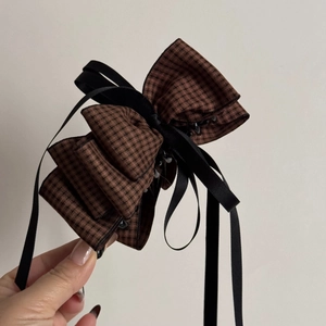 Detail view of large houndstooth bow hair clip with black satin ribbon and plastic teeth