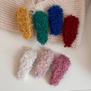 Close-up detail of plush lamb wool fabric textures on various colored BB hair clips
