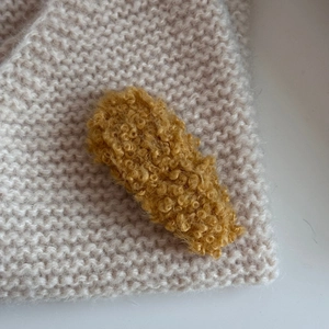 Close-up of a warm yellow plush hair clip featuring soft lamb wool texture and cozy design