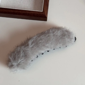 Dettaglio del grande fermaglio a banana in peluche grigio con robusti denti interni neri