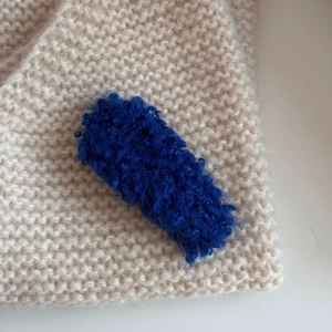 Detailed texture of dark blue teddy fleece hair clip on beige knit background