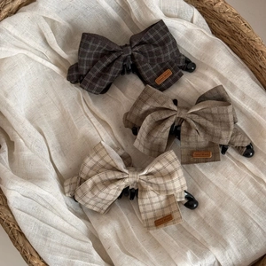 Three-piece set of fabric plaid bow hair clips in brown and beige within a woven basket