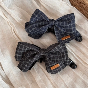 Detail of fabric bow banana clips in navy and charcoal with handmade leather labels