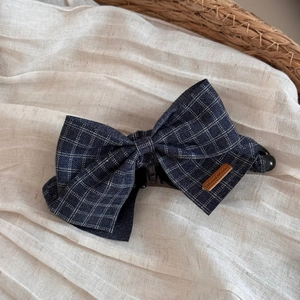 Detail of dark blue plaid fabric bow banana clip with a leather Hand Made label