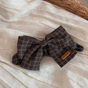 Detail of dark brown plaid fabric bow banana clip with a handmade leather label