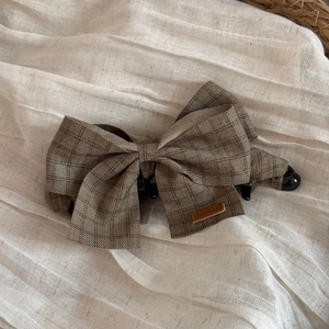 Detail of a brown plaid fabric bow banana hair clip featuring a handmade label on soft fabric