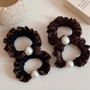 Detailed view of four leopard print hair scrunchies with elegant large white pearls
