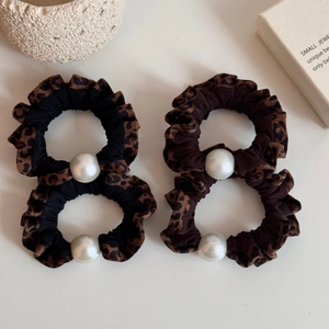 Elegant leopard print scrunchies with white pearl accents on minimalist warm white background