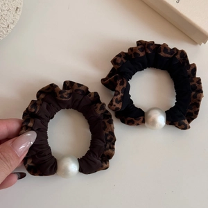 Detail of leopard print scrunchies set with faux pearls in black and coffee brown colors
