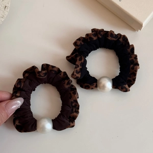 Detail of leopard print hair scrunchies with faux pearl bead accent and retro fabric texture