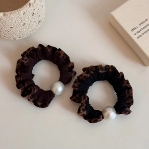 Close-up of leopard print scrunchies with large pearl accents in a two-piece accessory set