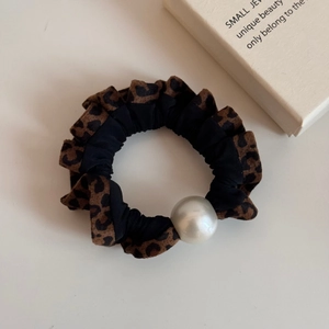 Close-up of leopard print scrunchie featuring elegant large pearl and black lace trim