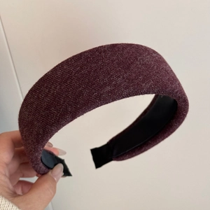 Detail showing thick dark burgundy knitted headband with textured fabric and non-slip lining