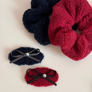 Detail of plush faux fur hair scrunchies and bow clips in navy blue and burgundy wine tones