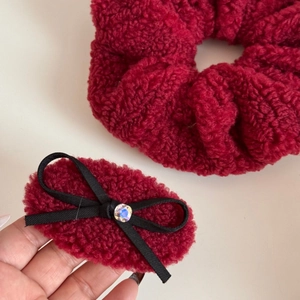 Detail of red plush faux shearling scrunchie and matching bow hair clip with rhinestone