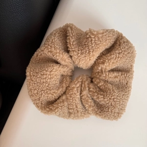 Close-up of caramel plush lamb wool oversized scrunchie with soft fluffy texture