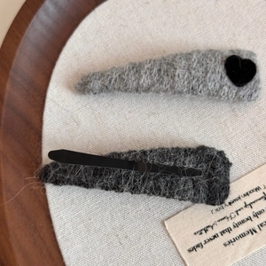 Close-up of knit texture and flocking heart detail on a soft grey triangular hair clip