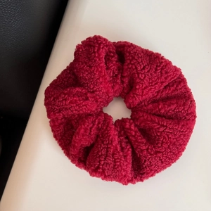 Detail of burgundy plush faux shearling hair scrunchie with soft autumn winter texture
