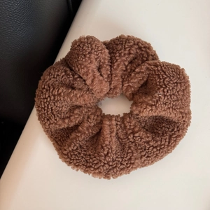 Close-up of soft brown teddy plush scrunchie with fluffy texture and warm fleece material