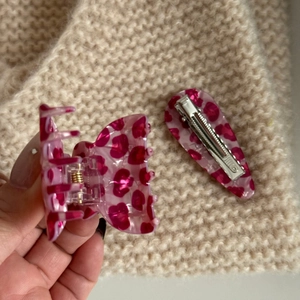 Detail view of pink leopard acetate hair claw and matching clip on knit fabric