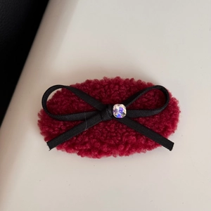 Macro detail of wine red plush faux fur hair clip with ribbon bow and sparkling rhinestone