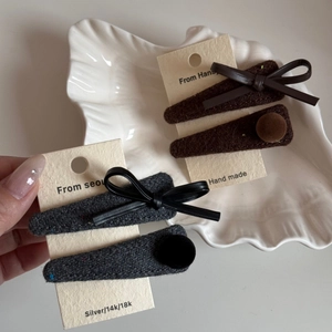 Elegant velvet and leather bow hair clips in grey and brown on a display card