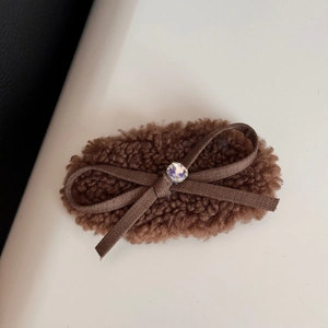 Close-up of brown plush hair clip with silk ribbon bow and sparkling central rhinestone
